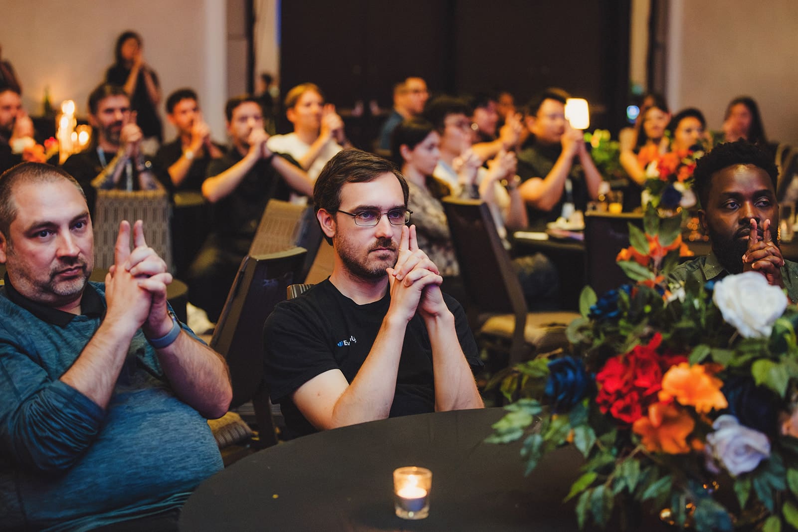 EvenUp guests at their dinner tables mirroring a gesture from the stage during the mentalism show